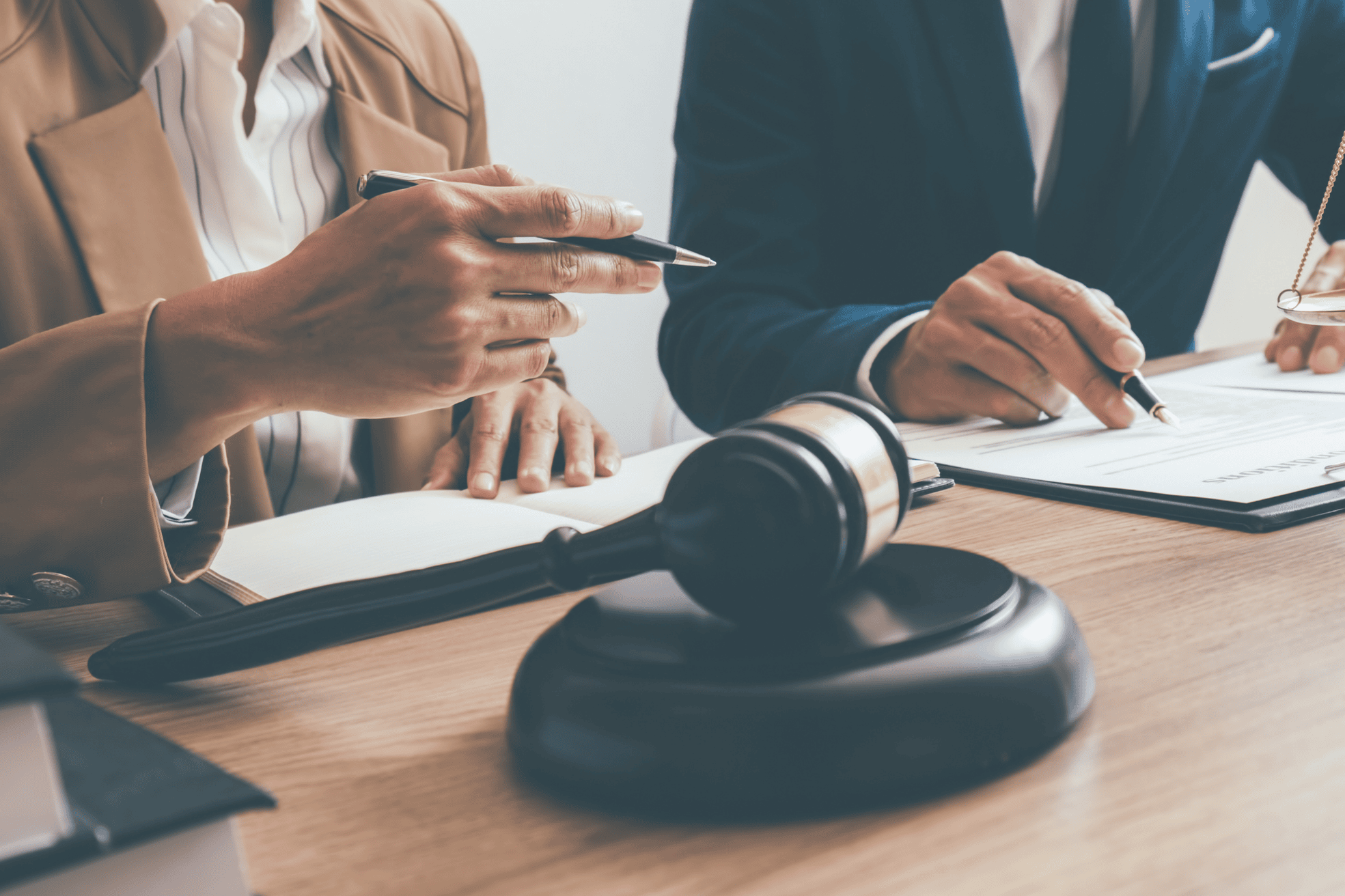 Professional legal consultation at a desk, hands gesturing over paperwork