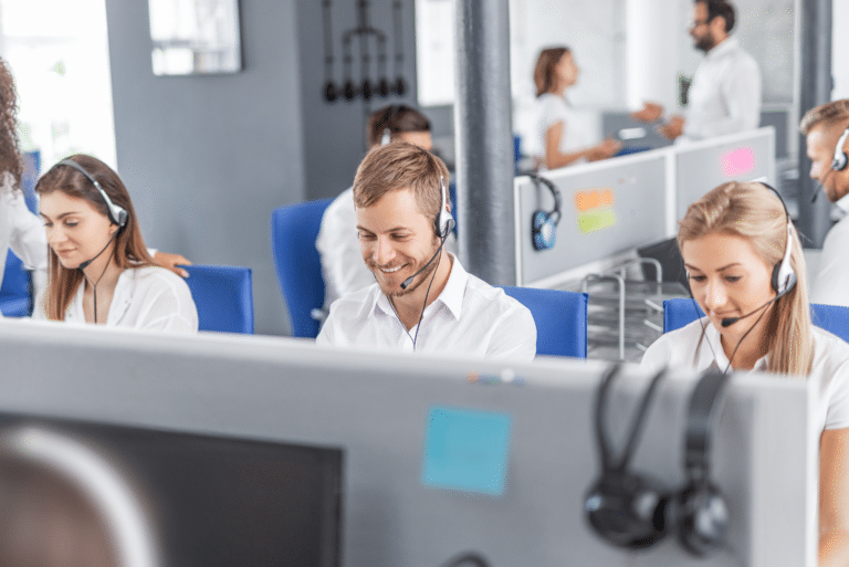 A group of IT support staff sitting at desks, each wearing a headset and working on their screens.
